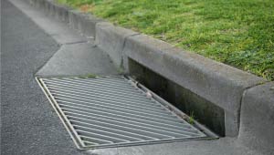 A picture of a street curb with a stormwater inlet.