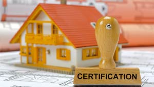 An animated picture of a blueprint laying on a table with a stamp that says Certification, and house sitting on top of the blueprint.